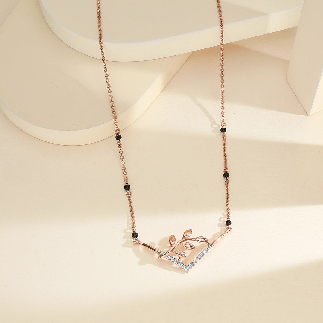 rose gold necklace with a leaf design on a beige background